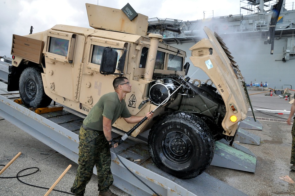 soldier using a pressure hose to clean the vehicle